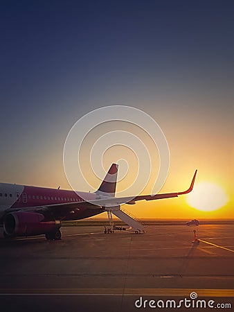 Airplane ready for boarding and takeoff at the airport with the view to the sunrise. Morning travel and holiday concept Stock Photo