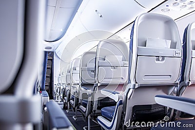 Airplane seats in cabin. Commercial aircraft cabin with rows of seats down the aisle. Economy class. Stock Photo