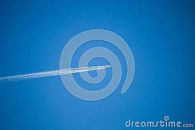 The airplane in the sky and the cluster of clouds left, the plane in the blue sky, and the cluster of clouds that it leaves. Stock Photo