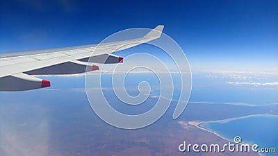 Airplane Window Seat -with beautiful view of wing of plane on flight and traveling in air over city and clouds. Stock Photo