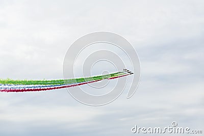 Airplanes on airshow with colorful bright trails of smoke against a blue sky, clouds. Aircraft, flying display and Stock Photo