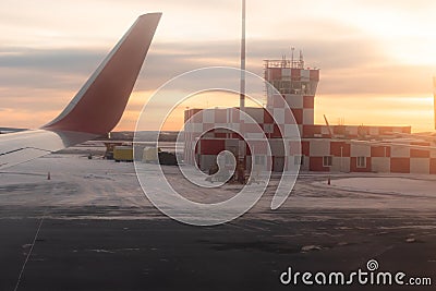 Airport building at dawn on the runway with flashing beacon painted in red and white checkerboard squares. airplane window view Editorial Stock Photo