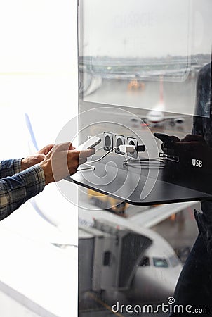 Airport public charger and man`s hands with smartphone. Airplane Stock Photo