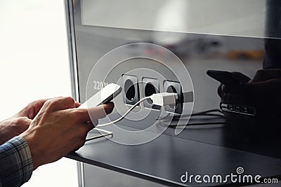 Airport public charger and man`s hands with smartphone. Airplane Stock Photo