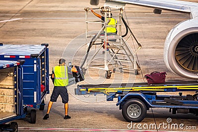 Airport worker loads baggage into an airplane Editorial Stock Photo