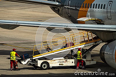 Airport workers loading baggage to an airplane Editorial Stock Photo