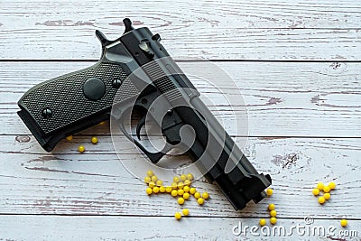 airsoft handgun with yellow bb, on white wooden background Stock Photo