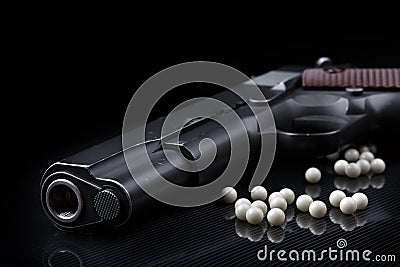 Airsoft pistol with bb bullets on black glossy surface Stock Photo