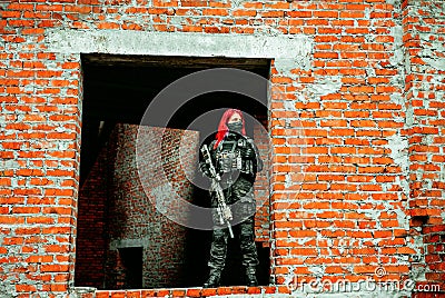 Airsoft red-hair woman in uniform with machine gun standing on ruins Stock Photo