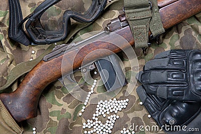 Airsoft rifle with protective glasses, gloves and white bullets Stock Photo