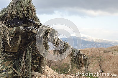 Airsoft sniper on hill rocks Stock Photo