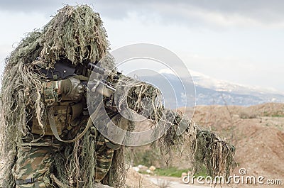 Airsoft sniper on hill rocks Stock Photo