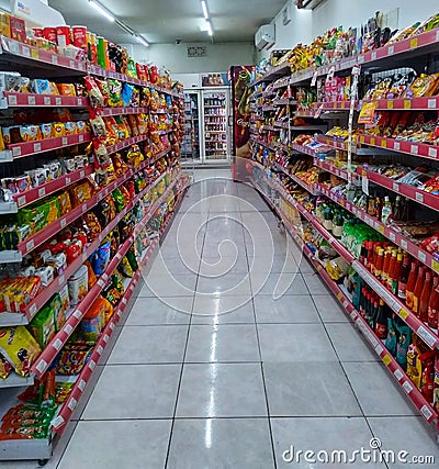 Aisle with various kinds of snacks and drinks on the shelves inside Alfamart (one of Indonesia local franchice Mini market Editorial Stock Photo