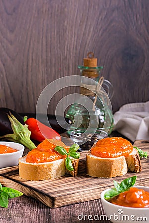 Ajvar delicious appetizer of pepper, eggplant and garlic on bread and in bowls. Vertical view Stock Photo
