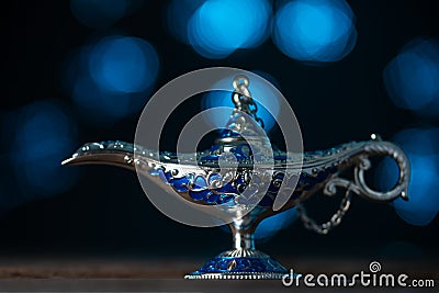 Aladdin`s magical genie lamp on soft blue lights background. Lamp of wishes concept. Antique arabian style Stock Photo