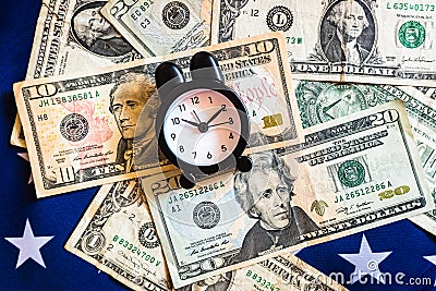 Alarm clock on American flag with money, to choose the best time to invest Stock Photo