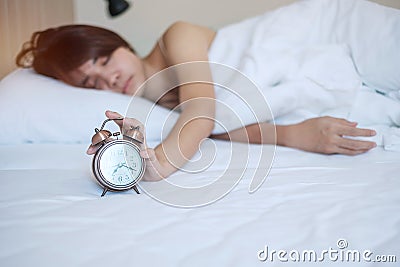 Alarm clock and asian woman hand stop time in bed while sleeping, young adult female wake up late in the morning. fresh relax, Stock Photo