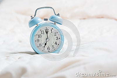 Alarm clock on bed Stock Photo