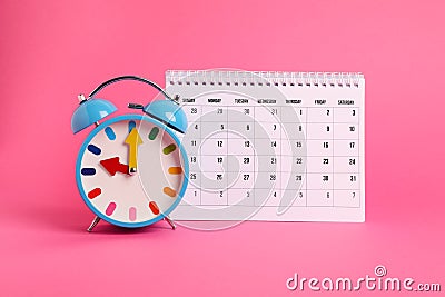 Alarm clock and calendar on pink. Reminder concept Stock Photo