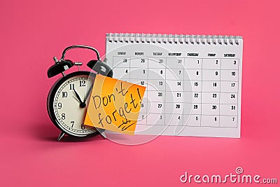 Alarm clock, calendar and reminder note with phrase Don`t forget on pink Stock Photo