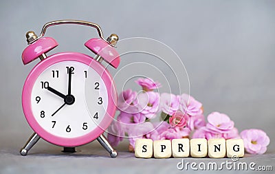 Alarm clock and flowers, spring forward, daylight savings time concept Stock Photo