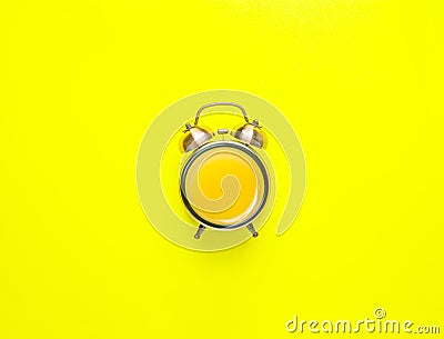 Alarm clock with fresh orange juice as dial pice in the middle. Creative food collage. Morning healthy breakfast energy fitness Stock Photo