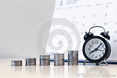 Alarm clock and money coins stack with calendar background, saving money Stock Photo