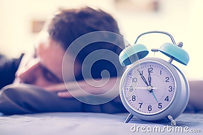 Alarm clock in the morning. Young man sleeps in the blurry background Editorial Stock Photo