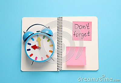 Alarm clock, notebook and reminder note with phrase Don`t forget on light blue background, top view Stock Photo