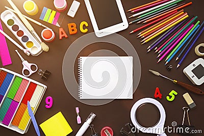 Alarm clock, paint, pencils and scissors. School accessories on a yellow background. School and office supplies frame Stock Photo