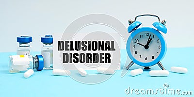 An alarm clock, pills, injections and a card with the inscription - Delusional Disorder Stock Photo