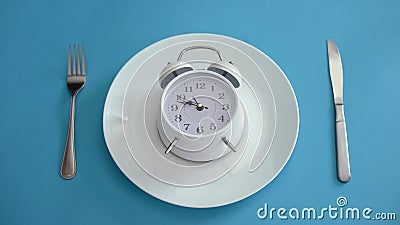 Alarm clock on plate, adhere to diet time, proper nutrition, discipline, closeup Stock Photo