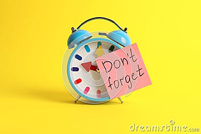 Alarm clock and reminder note with phrase Don`t forget on yellow background Stock Photo