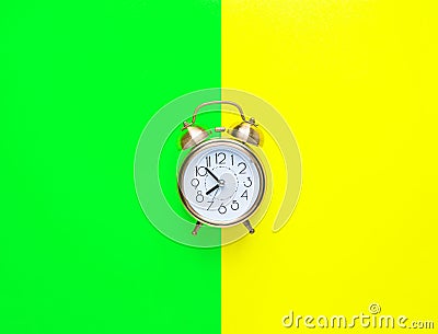 Alarm clock showing eight o`clock on bright duo tone yellow neon green background. Flat lay. Morning sunlight. New day beginning Stock Photo