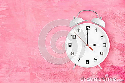 Alarm clock with twin bells and ringer showing 3 o'clock on pink background Stock Photo