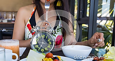 Alarm clock with woman eating a healthy food as Intermittent fasting, time-restricted eating-Diet concept Stock Photo