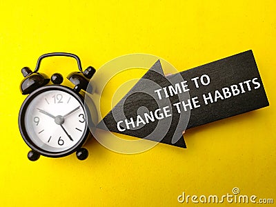 Alarm clock and wooden arrow with text TIME TO CHANGE THE HABBITS Stock Photo