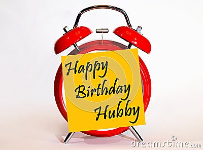 An alarm clock and a yellow note with text happy Birthday hubby. Stock Photo