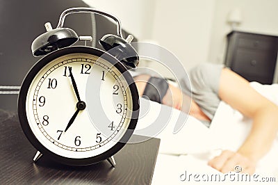 Alarm clock and young man sleeping in bed with a sleep mask Stock Photo