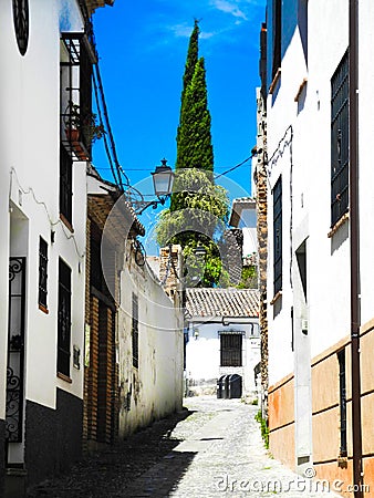 Albaicin, Old muslim quarter, district of Granada in Spain. Narrow street with white houses. Blue summer sky. Stock Photo