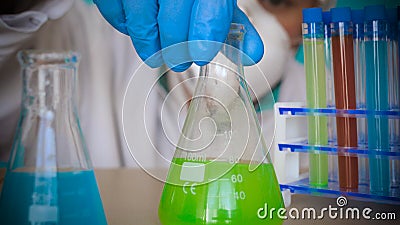 The alchemist checks the test tubes with a test of different compositions, in a white coat, a respirator, goggles, rubber white gl Stock Photo