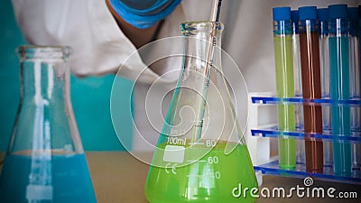 The alchemist checks the test tubes with a test of different compositions, in a white coat, a respirator, goggles, rubber white gl Stock Photo