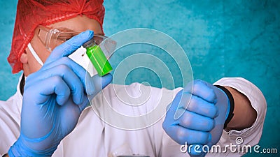 The alchemist checks the test tubes with a test of different compositions, in a white coat, a respirator, goggles, rubber white gl Stock Photo