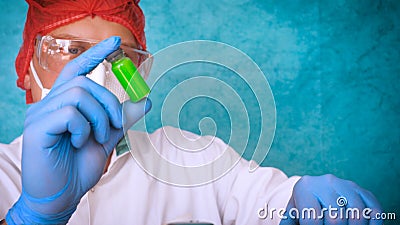 The alchemist checks the test tubes with a test of different compositions, in a white coat, a respirator, goggles, rubber white gl Stock Photo