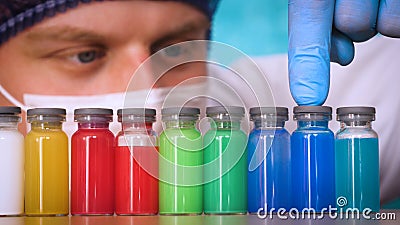 The alchemist checks the test tubes with a test of different compositions, in a white coat, a respirator, goggles, rubber white gl Stock Photo