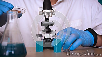 The alchemist checks the test tubes with a test of different compositions, in a white coat, a respirator, goggles, rubber white gl Stock Photo