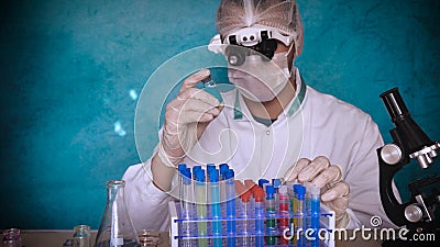 The alchemist checks the test tubes with a test of different compositions, in a white coat, a respirator, goggles, rubber white gl Stock Photo