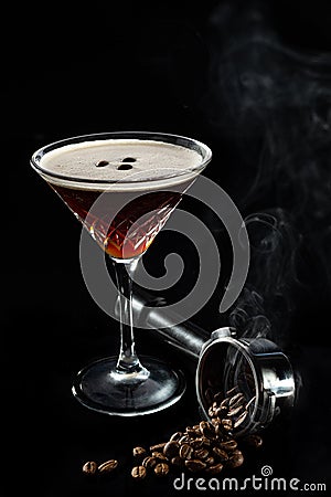 Espresso Martini cocktails garnished with coffee beans, beans in espresso holder in smoke and on black background Stock Photo