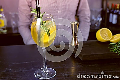 Alcohol cocktail with sparkling wine, ice and liquor , lemon and rosemary in wineglass on bar counter, close-up view. Stock Photo