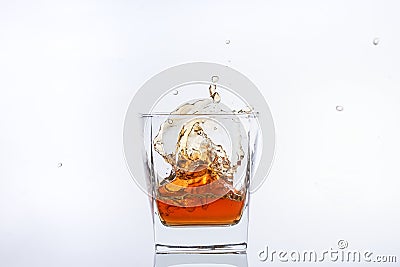 Alcohol in the glass. Whiskey with ice. Rum with ice. Brown brandy with ice. Three ice cubes in a glass with alcohol. Stock Photo